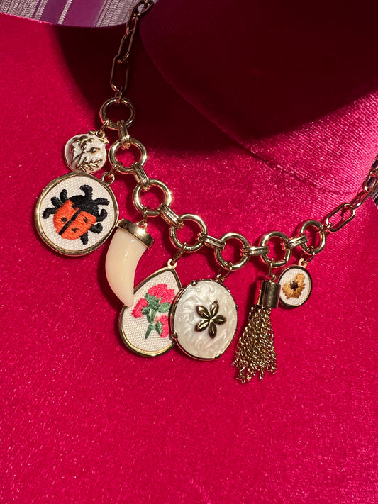 Collana girocollo catena dorata con charms dorati in tessuto con fiori e coccinelle , corno bianco