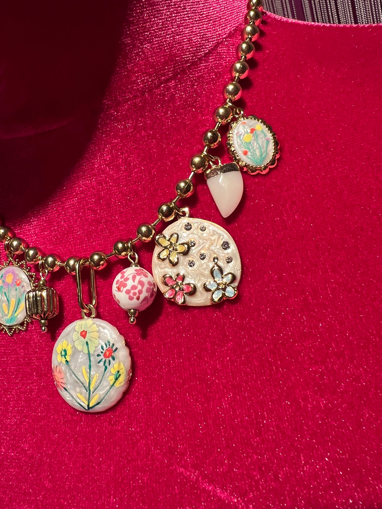 Collana girocollo con palline dorate charms floreali su base bianca