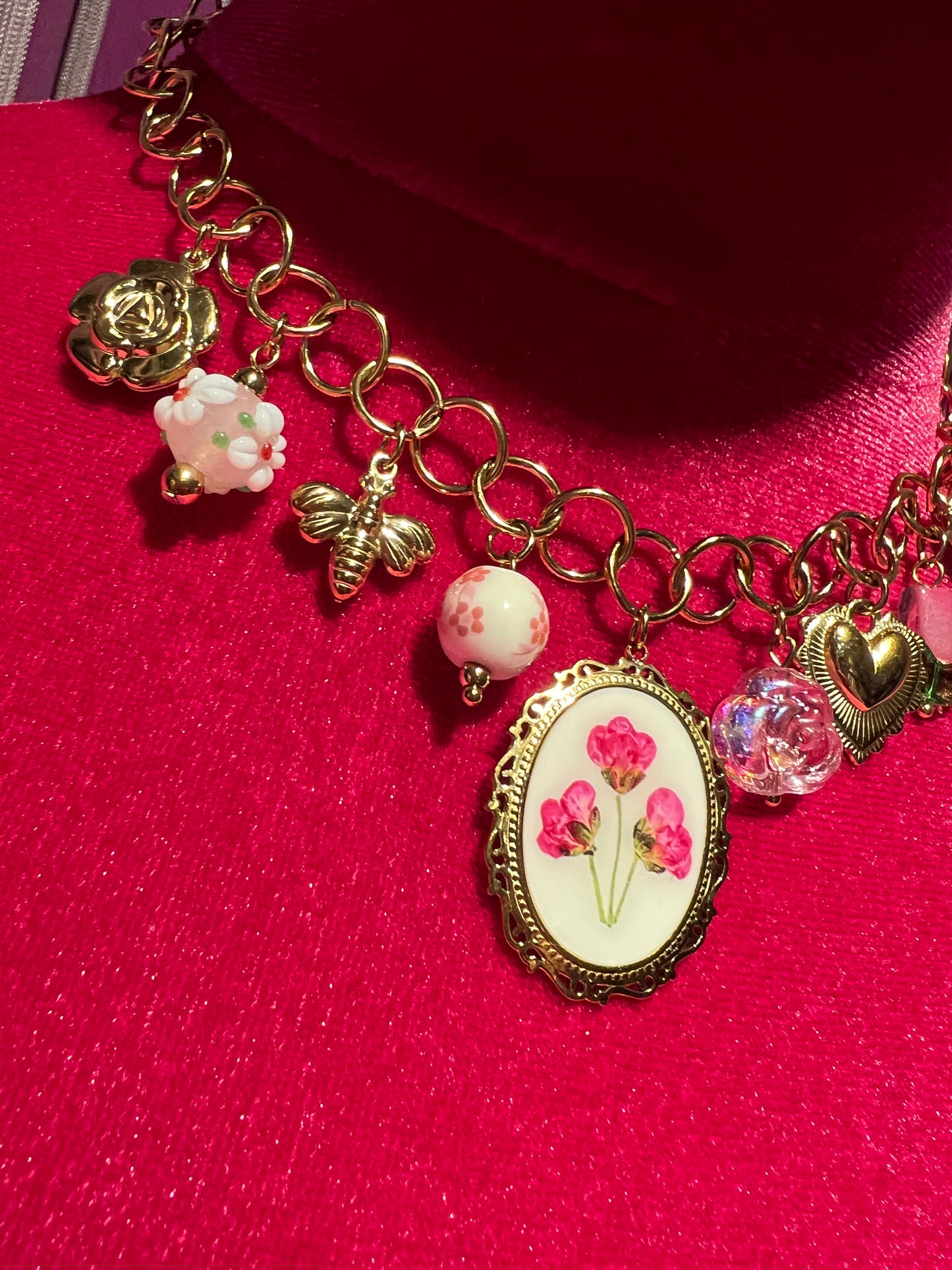 Collana girocollo dorata con ciondolo smaltato con disegno floreale e charms