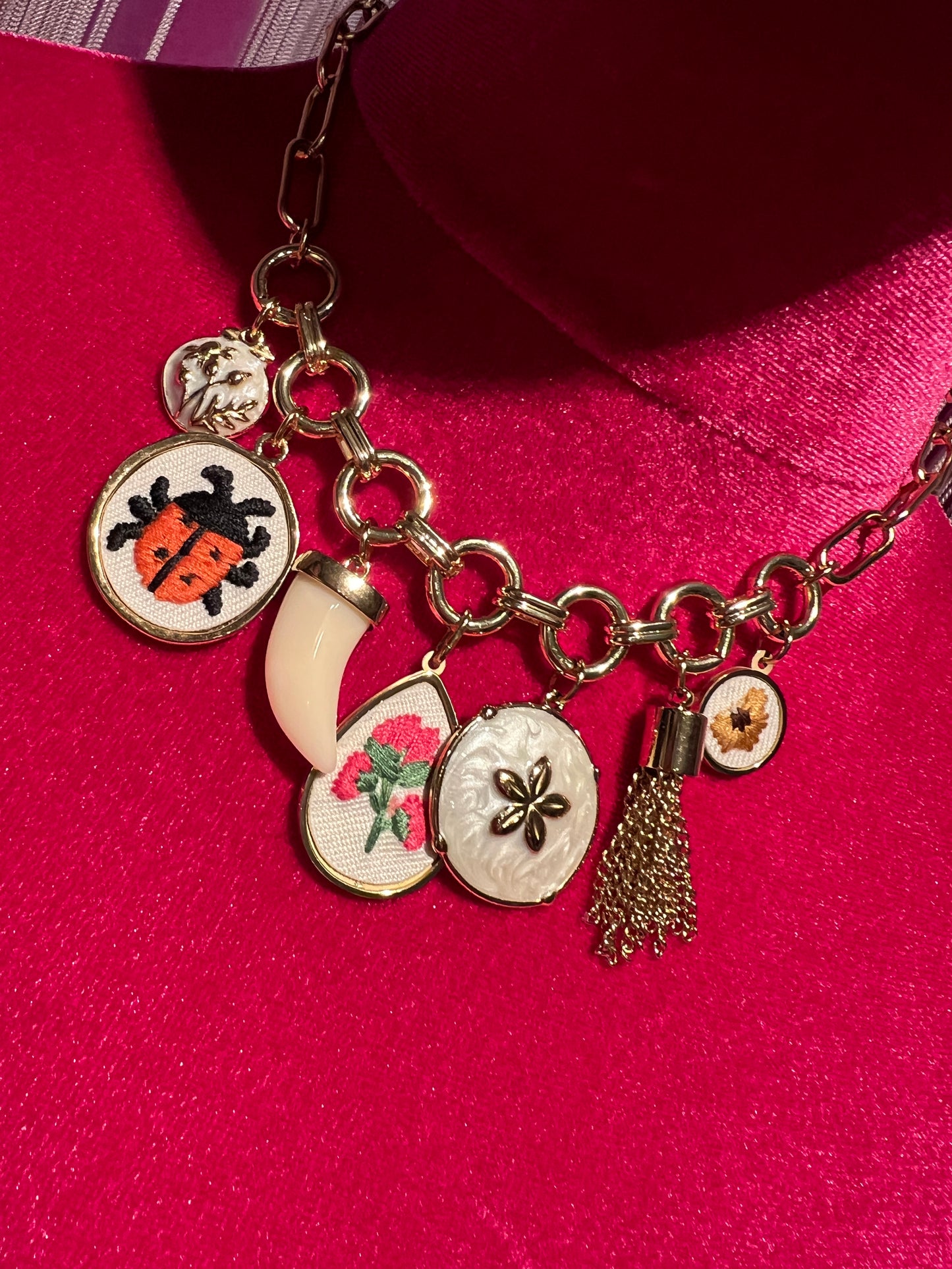 Collana girocollo  catena dorata con charms dorati in tessuto con fiori e coccinelle , corno bianco