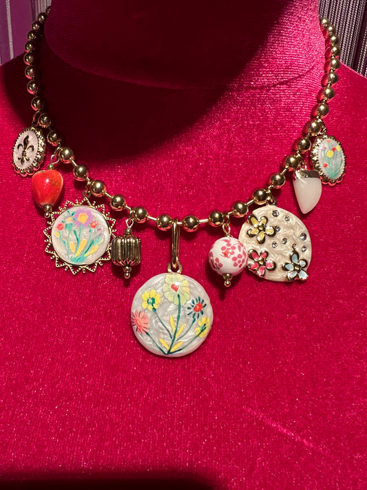 Collana girocollo con palline dorate charms floreali su base bianca