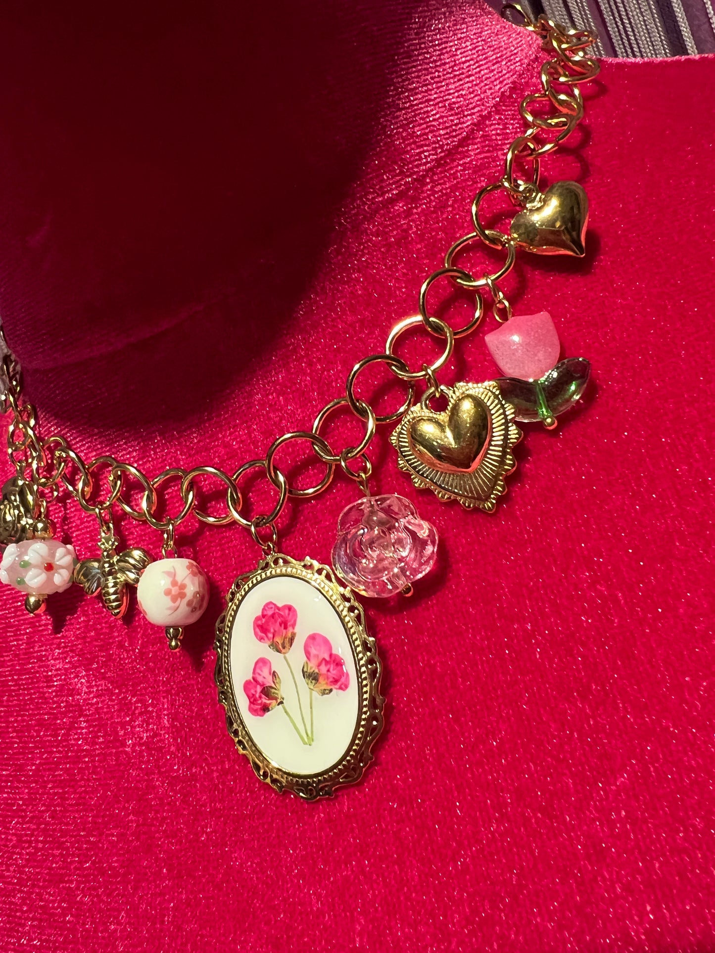 Collana girocollo dorata con ciondolo smaltato con disegno floreale e charms