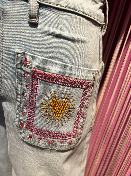 Mon amour Paris jeans denim chiaro tasche con ricamo cuore e scritta bisous bisous Le taglie dei capi sono espresse in formato internazionale (S, M, L, XL…) e accompagnate dalla corrispondente taglia francese indicata in etichetta