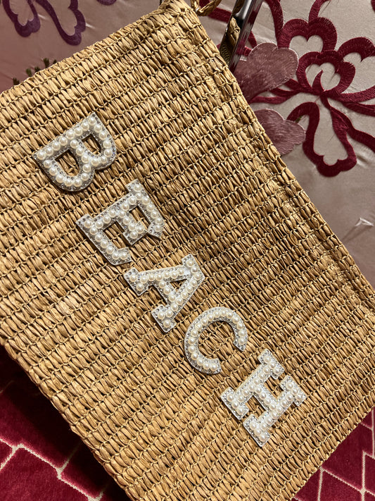 Pochette in paglia intrecciata con scritta “ Beach” perline