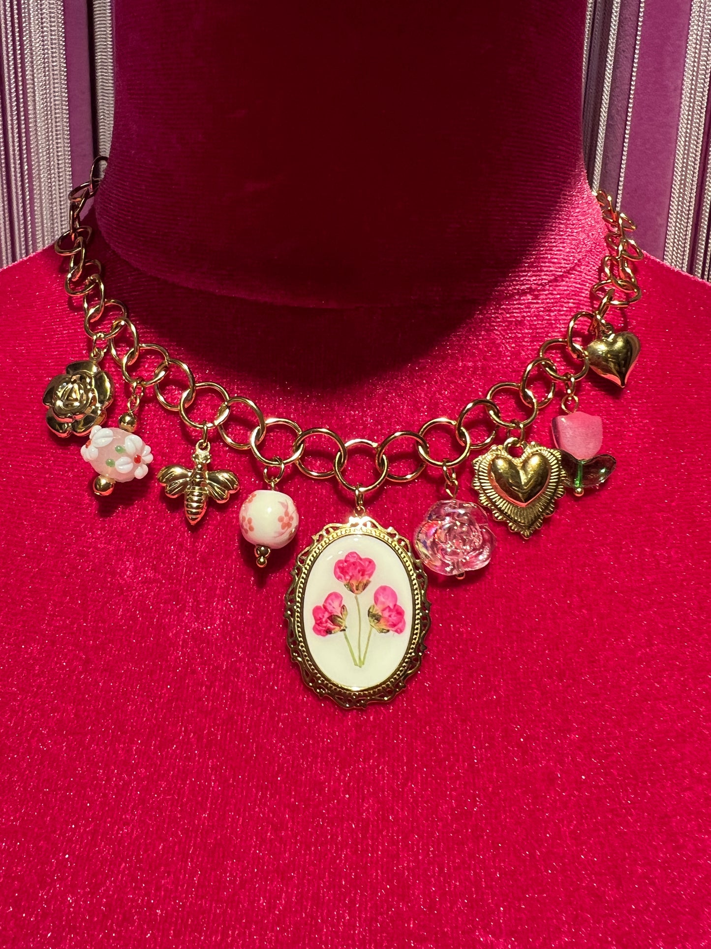 Collana girocollo dorata con ciondolo smaltato con disegno floreale e charms